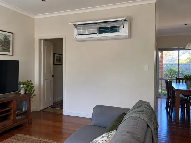 Clean split system indoor head with open front panel and visible filters on a living room wall in Tea Tree Gully